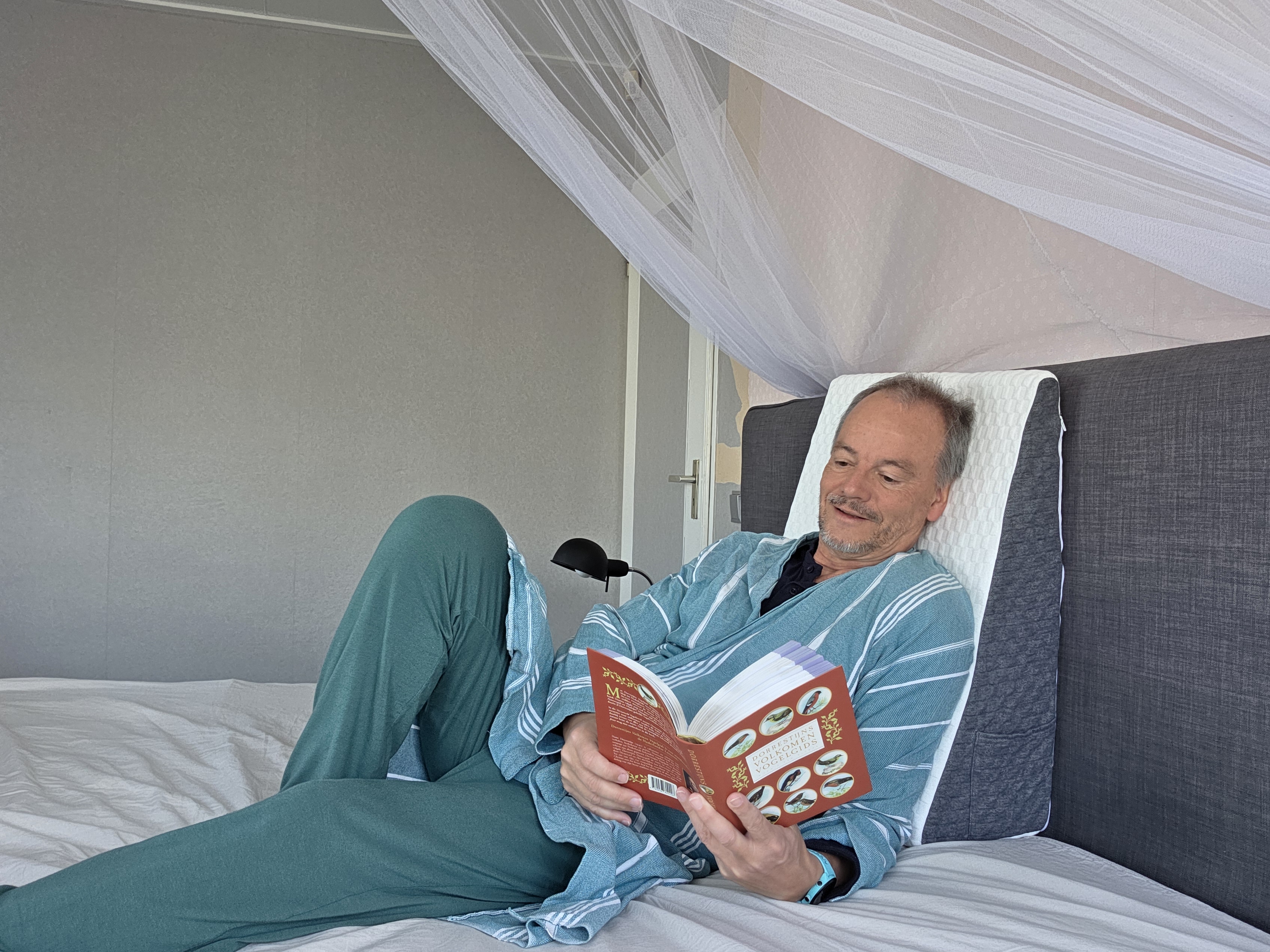 Bas de Leeuw model liggend in slaapkamer met kamerjas en boek